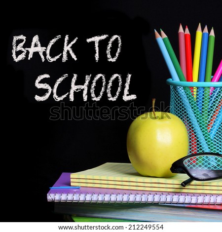 Back to School. School Supplies over black. An apple and colored pencils on pile of books.