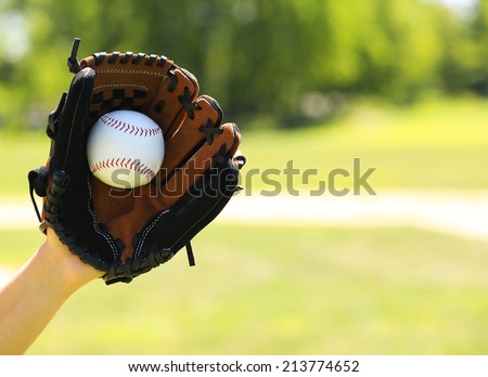 Hand of Baseball Payer with Glove and Ball over Field