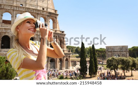 Happy Tourist and Coliseum, Rome. Cheerful Young Blonde Woman with Camera in Italy. Travel in Europe