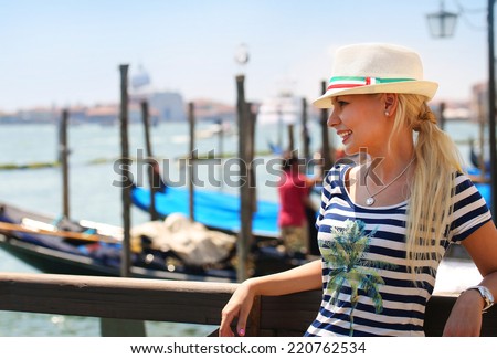 Happy Tourist and Gondolas in Venice, Italy. Cheerful Young Blonde Woman with Hat. Travel in Europe