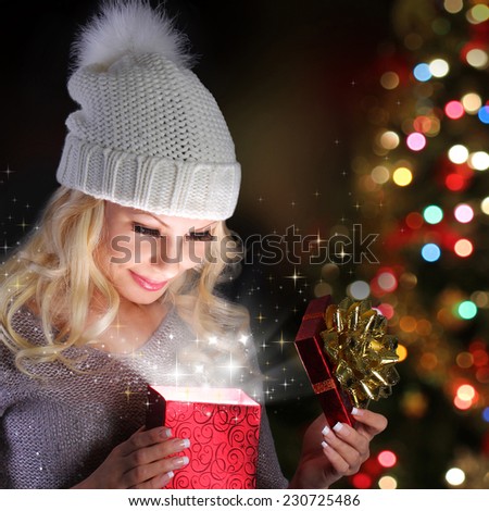 Christmas Miracle. Smiling Blonde Girl Opening Gift Box over lights of Christmas tree