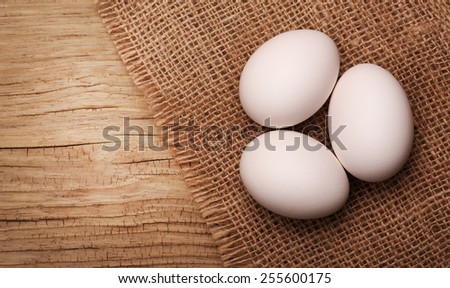 White eggs on burlap over wooden background