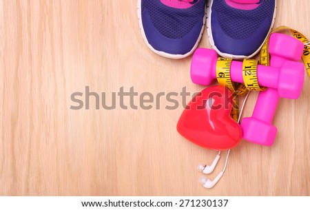 Sport Equipment for Cardio. Sneakers, dumbbells, measuring tape and earphones on wooden background