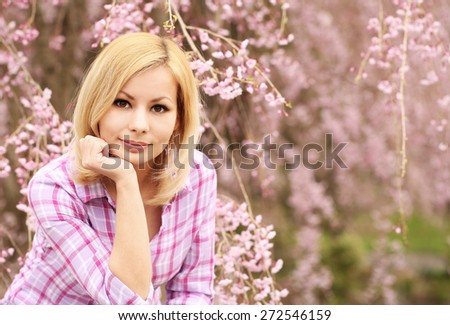 Girl with Cherry Blossom. Beautiful Blonde Young Woman with Sakura. Spring Flowers. Portrait