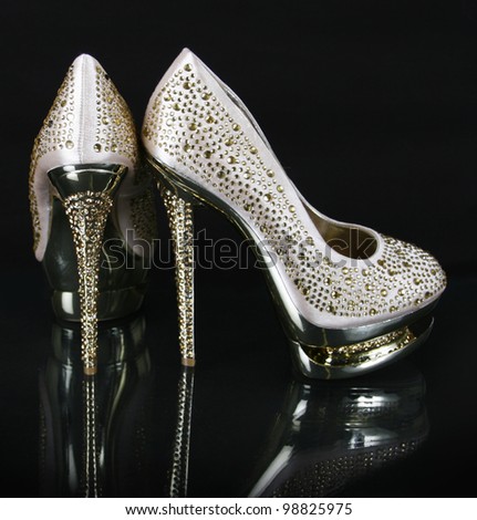 crystals encrusted gold shoes on black background