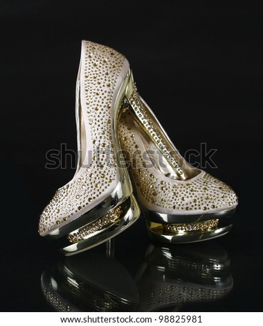 crystals encrusted golden shoes on black background