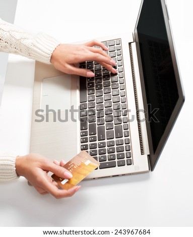 woman\'s hand enters data using laptop and holding credit card in the other hand, isolated on white background.