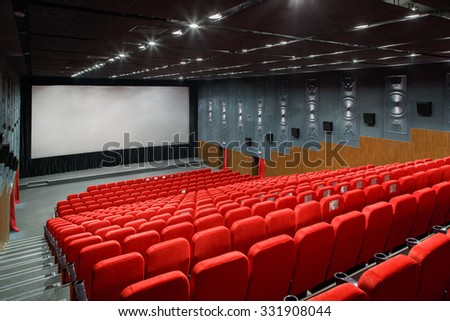 interior of a large room with a lot of theater red armchair and large screen.