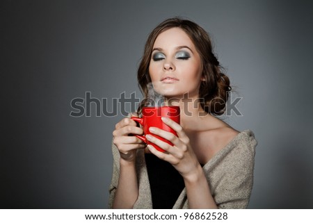 girl with a cup in his hand, breathes fragrance. Isolated on gray background.