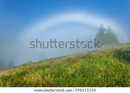 Carpathian Mountains. White rainbow in the mist, slopes covered with green grass.