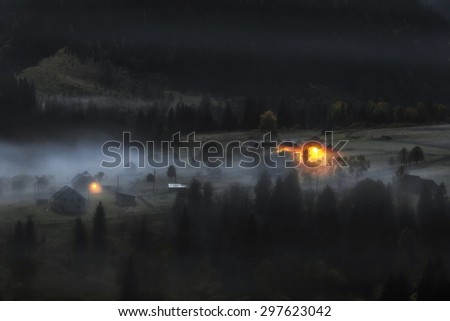 Carpathian Mountains. Moonlit Night in the mountains, the village on the hill in the fog.