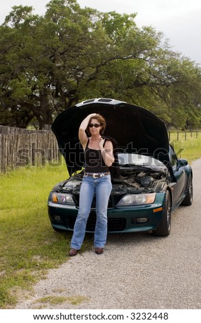 Woman standing by her car with the hood open as if experiencing car trouble.