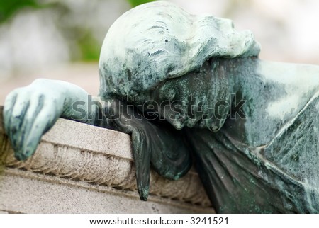Tomb with a bronze statue of a grieving woman that is covered with green patina from years of exposure to the elements.
