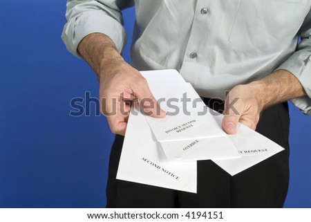 A man holding a several white envelopes with past due notices on them.