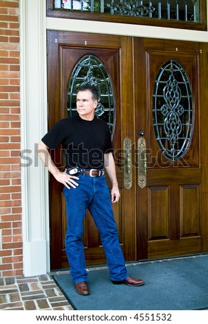 Man standing in front of beautiful wooden double doors with ornate glass work.