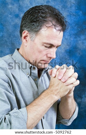 A man in a posture of prayer with head bowed and hands together.