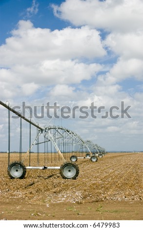 An agriculture sprinkler irrigation system stationed in a large uncultivated field.