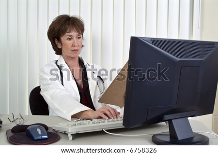 A woman dressed as a doctor working on a computer.