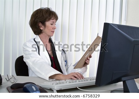 A woman dressed as a doctor entering information from a report into a computer.