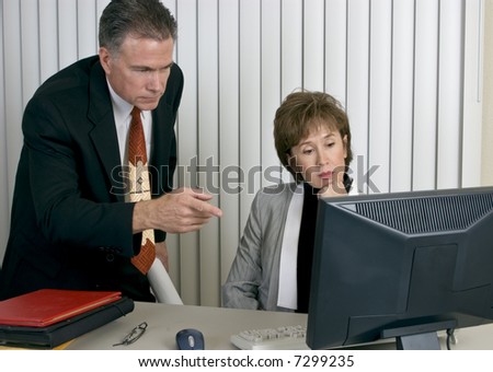 Co-workers discussing or analyzing something on a computer monitor.