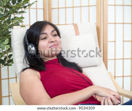 A young woman relaxing in a chair with headphones over her ears.