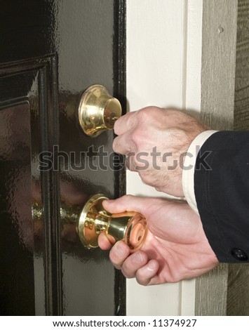 A man with a key in one and the door knob in another ready to unlock his door.