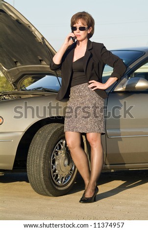 A woman on a cell phone next to a car that appears to be out of service.