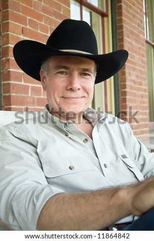 A man wearing a black cowboy hat and a peaceful, friendly smile on his face.