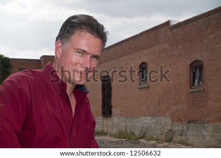 A smiling man with the back of and old brick building in the background.