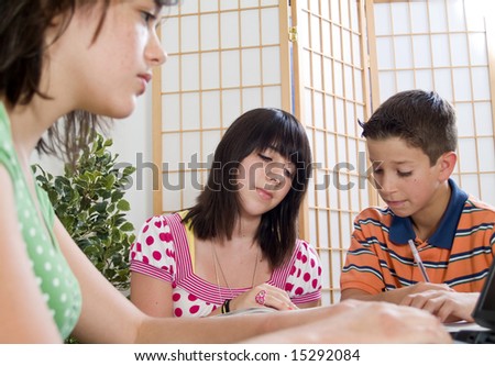 Three adolescents studying together with focus on boy and girl in the background.