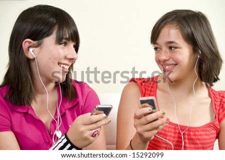 Two girls enjoying listening to music on their miniature music players.