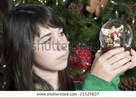 A lovely young girl looks thoughtfully at the nativity scene inside the music globe.
