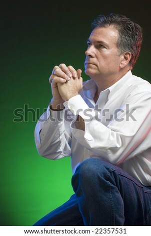 stock photo : A man kneeling in prayer, with green, blue and red gels