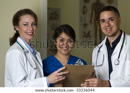 Two doctors and nurse discussing lab results stop and smile at the camera.
