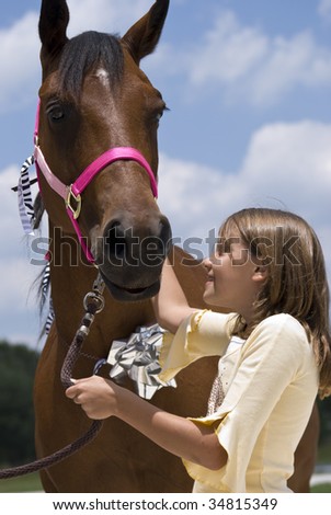 A little girl looking with joy and affection at a beautiful horse that has been given to  her as a gift on her birthday.