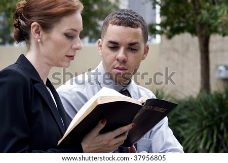 A man and a woman who are sitting together reading from the Holy Bible, perhaps while on break from work.