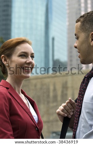 Business partners or coworkers engaged on friendly conversation with tall skyscrapers as the backdrop.
