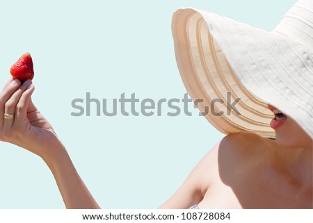 woman eating strawberry wearing floppy hat covering most of face, except lips