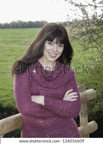 Woman standing by farmers fence in fashionable jumper