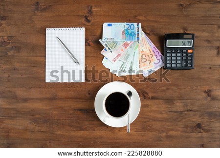 cup of coffee, calculator,  notepad and euro money on the table