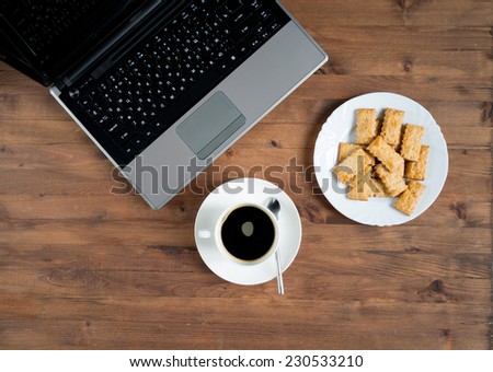 laptop, coffee, and  plate of cookies lay on the old table