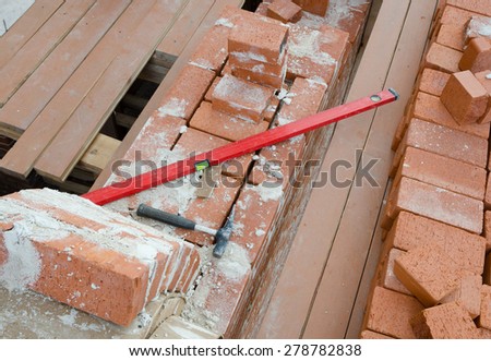 Mason bricklaying background with  level, hammer and clay brick blocks