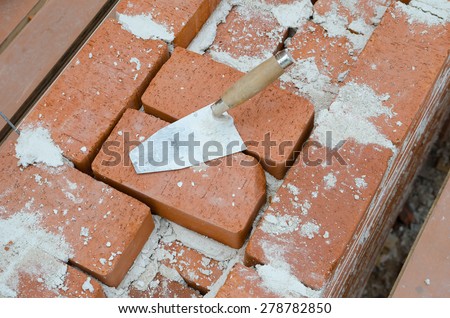 Mason bricklaying background with trowel and clay brick blocks