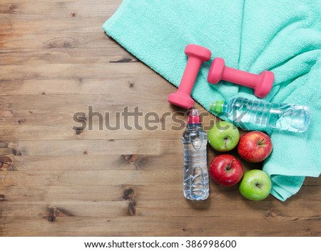 Healthy lifestyle concept. colored Apples dumbbells sport water bottles and turquoise towel on wooden table