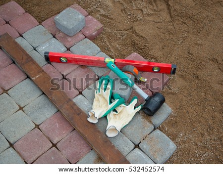 Pavement details, stone blocks rubber hammer level gloves and tape measure