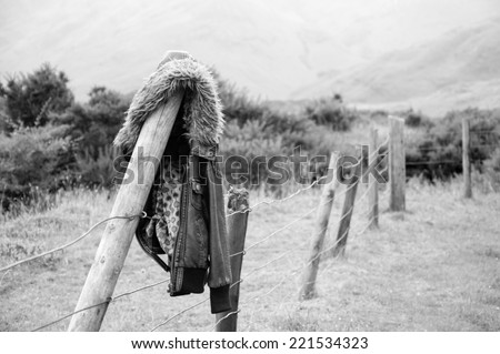 vintage leather jacket left hanging on a fence post