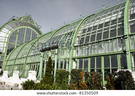 an antique greenhouse with aged steel under a grey overcast sky