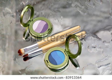 Eye shadows / Blue and purple eye shadow and makeup brush placed on a wet mirror