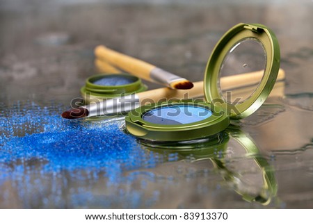 Blue eye shadow / Blue eye shadows and makeup brushes placed on a wet mirror