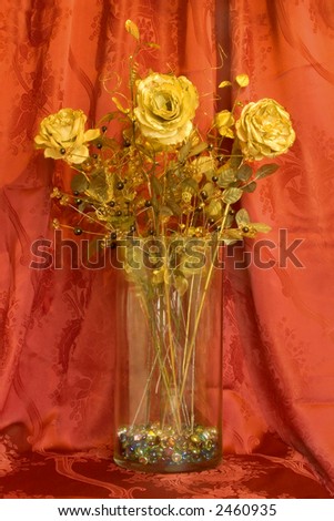 Golden roses in glass bowl, red background